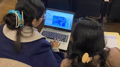 two researchers look at GBD Compare data visualization on a laptop screen