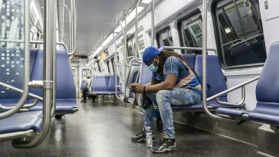 Man wearing a mask rides on a mostly-empty subway